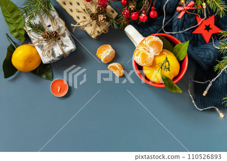 Winter composition with fir branches, present, cones and tangerines on a blue background. Cozy winter mood. View from above. Copy space. Winter composition with fir branches, present, cones and tangerines on a blue background. Cozy winter mood. View from above. Copy space. 110526893