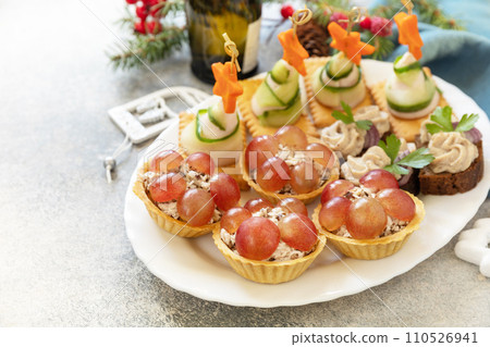 Creative appetizers set christmas. Christmas trees of ham, cucumber, cheese and star of carrot on crackers, tartlets with chicken and grapes, creamy pate sandwiches of herring on a rye bread. Copy Creative appetizers set christmas. Christmas trees of ham, cucumber, cheese and star of carrot on crackers, tartlets with chicken and grapes, creamy pate sandwiches of herring on a rye bread. Copy 110526941