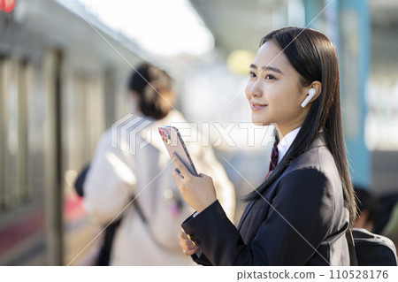 戴著智慧型手機、戴著耳機搭火車上學的女高中生的照片 戴著智慧型手機、戴著耳機搭火車上學的女高中生的照片 110528176