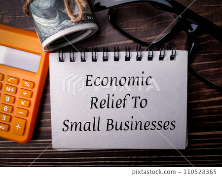 Top view banknotes,glasses,and calculator with text Economic Relief To Small Businesses on wooden background. Top view banknotes,glasses,and calculator with text Economic Relief To Small Businesses on wooden background. 110528365