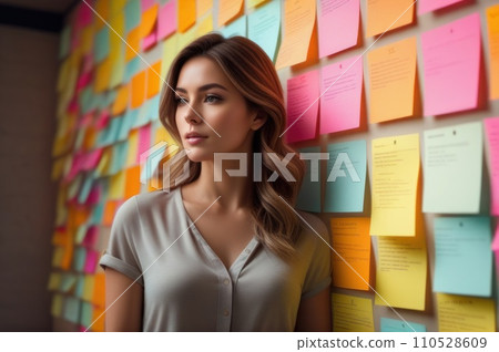 A woman standing in front of a wall full of colorful sticky notes. Young woman working in office and use post it notes to share idea. Communicating together in creative office. Brainstorming concept.. 110528609