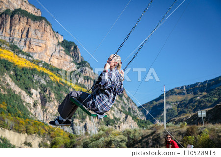 Girl swinging on a swing in the mountains Girl swinging on a swing in the mountains 110528913