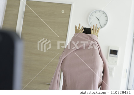 A young woman puts her hand out of her clothes while changing clothes A young woman puts her hand out of her clothes while changing clothes 110529421