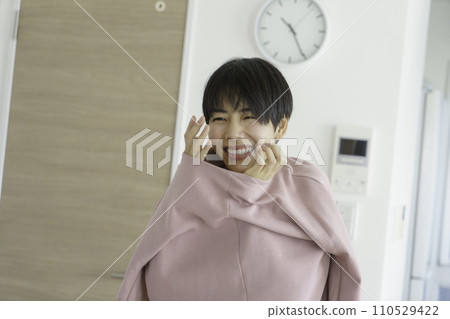 A young woman smiling with her neck and hands out of her clothes 110529422