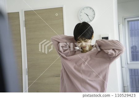 Young woman changing into a pink sweatshirt in the morning 110529423