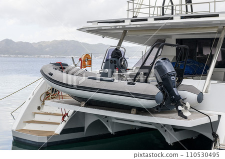 Inflatable tender motor boat on swim platform of superyacht. Inflatable dinghy with outboard engine. Power boat. 110530495