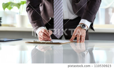Male arm in suit and tie fill form clipped to pad 110530923