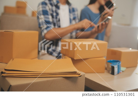 Two Asian blogger showing clothes in front of the camera to recording vlog video live streaming at her shop. Online Shopping Cart notion. on sofa at home 110531301