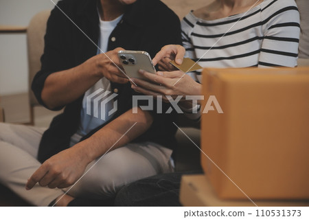 Two Asian blogger showing clothes in front of the camera to recording vlog video live streaming at her shop. Online Shopping Cart notion. on sofa at home 110531373