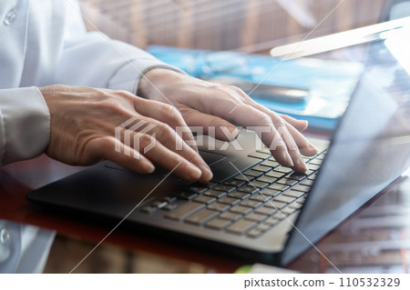 The doctor clicks on the laptop keyboard. 110532329