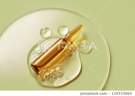 Ampoule in a drop of cosmetic gel on a green background. 110533664