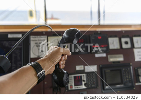Navigational control panel and VHF radio with hand. Radio communication at sea. Working on the ship's bridge. Navigational control panel and VHF radio with hand. Radio communication at sea. Working on the ship's bridge. 110534029