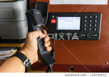 Navigational control panel and VHF radio with hand. Radio communication at sea. Working on the ship's bridge. 110534033