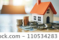 House and stack of coins with white background. Home savings concept. Energy saving. Cost of the house. Cost of living. Savings for home goal. Dreaming of home. 110534283