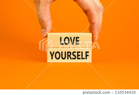 Love yourself symbol. Concept words Love yourself on beautiful wooden blocks. Beautiful orange table orange background. Businessman hand. Psychology love yourself concept. Copy space. 110534420