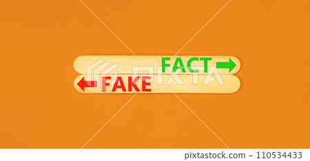Fact or fake symbol. Concept word Fake and Fact on beautiful wooden stick. Beautiful orange table orange background. Business and fact or fake concept. Copy space. Fact or fake symbol. Concept word Fake and Fact on beautiful wooden stick. Beautiful orange table orange background. Business and fact or fake concept. Copy space. 110534433
