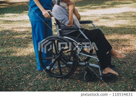 Young asian care helper with asia elderly woman on wheelchair relax together park outdoors to help and encourage and rest your mind with green nature. Help support yourself to learn to walk. walker Young asian care helper with asia elderly woman on wheelchair relax together park outdoors to help and encourage and rest your mind with green nature. Help support yourself to learn to walk. walker 110534631