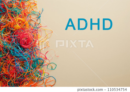 Text ADHD and multi-colored tangled threads on a beige background with copy space, concept of neurodiversity and mental problems 110534754