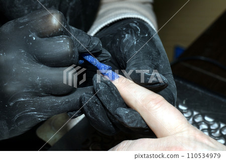 Manicure. Blue varnish is applied to the fingernail. 110534979
