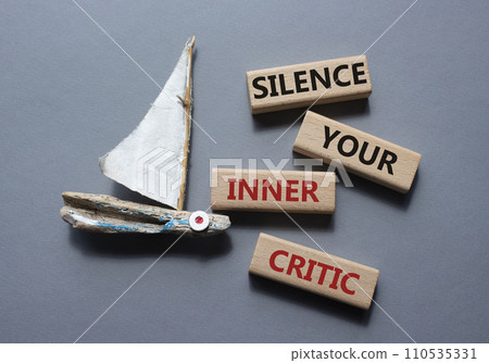 Silence your inner critic symbol. Wooden blocks with words Silence your inner critic. Beautiful grey background with boat. Business and Silence your inner critic concept. Copy space. 110535331