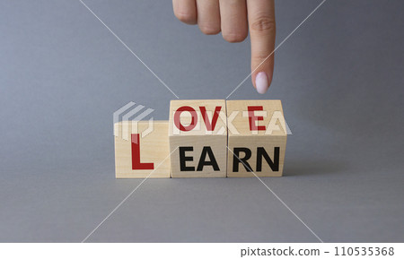 Love and Learn symbol. Businessman hand points at turned wooden cubes with words Learn and Love. Beautiful grey background. Lifestyle and Love and Learn concept. Copy space. 110535368