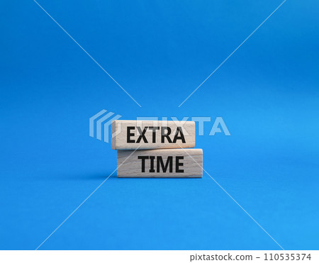 Extra time symbol. Concept word Extra time on wooden blocks. Beautiful blue background. Business and Extra time concept. Copy space 110535374