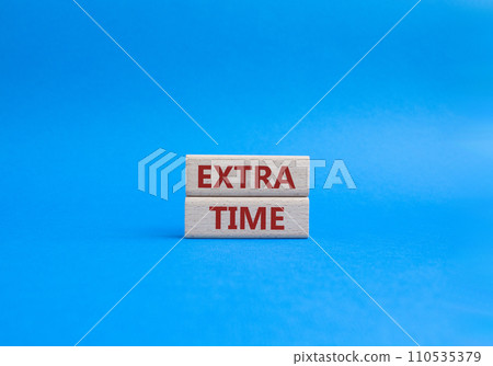 Extra time symbol. Concept word Extra time on wooden blocks. Beautiful blue background. Business and Extra time concept. Copy space 110535379