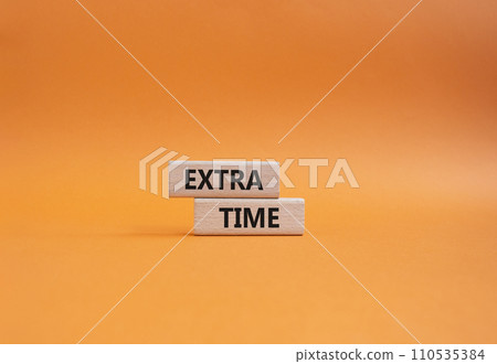 Extra time symbol. Concept word Extra time on wooden blocks. Beautiful orange background. Business and Extra time concept. Copy space Extra time symbol. Concept word Extra time on wooden blocks. Beautiful orange background. Business and Extra time concept. Copy space 110535384