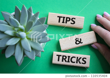 Tips and tricks symbol. Wooden blocks with words Tips and tricks. Beautiful green background with succulent plant. Businessman hand. Business concept and Tips and tricks. Copy space. 110535404