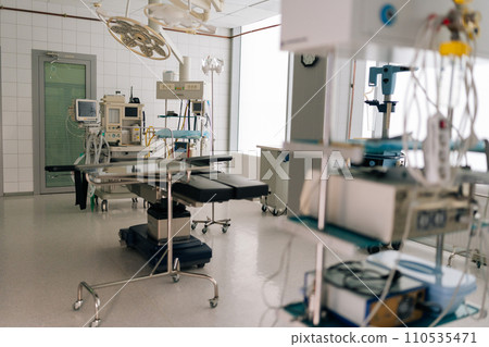 Light interior of modern operating room and equipment in hospital, no people. Medical device for surgeon surgical emergency patient. Light clean surgical theatre with diverse equipment. Light interior of modern operating room and equipment in hospital, no people. Medical device for surgeon surgical emergency patient. Light clean surgical theatre with diverse equipment. 110535471