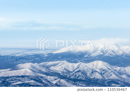 Aerial view of Mt. Shibetsu (front left), Mt. Samakkenupuri (center front), Mt. Shari (back), Shari Plain, and Sea of Okhotsk 110536467