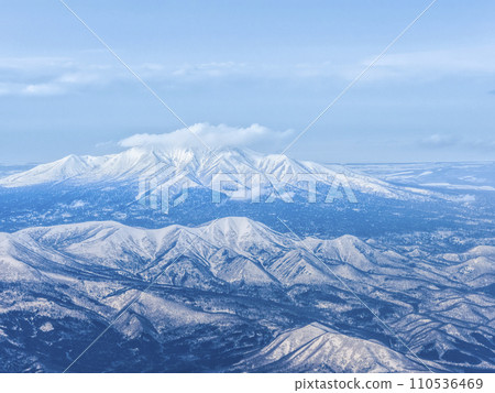 Aerial view of Mt. Shibetsu (front left), Mt. Samakkenupuri (center front), Mt. Shari (back), Shari Plain, and Sea of Okhotsk 110536469