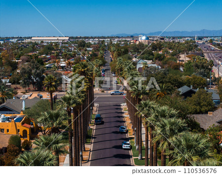 An aerial shot of Californian palms with an empty road. Palm trees and desert mountain in Palm Springs, California. An aerial shot of Californian palms with an empty road. Palm trees and desert mountain in Palm Springs, California. 110536576