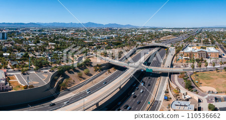 Aerial view of the highway and crossroads intersections in Phoenix, USA. Top up aerial drone view of elevated road and traffic junctions in USA metropolis during sunny day. Aerial view of the highway and crossroads intersections in Phoenix, USA. Top up aerial drone view of elevated road and traffic junctions in USA metropolis during sunny day. 110536662