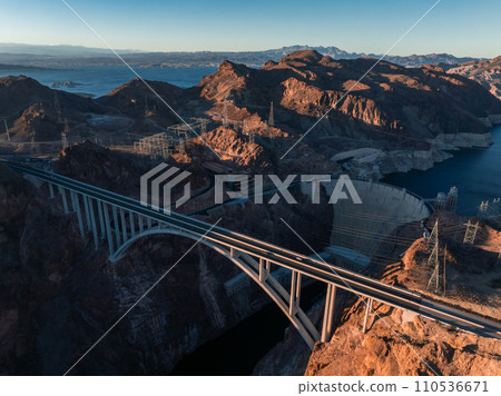 Hoover Dam on the Colorado River straddling Nevada and Arizona at dawn from above. Aerial view of Hoover Dam and the Colorado River Bridge Hoover Dam on the Colorado River straddling Nevada and Arizona at dawn from above. Aerial view of Hoover Dam and the Colorado River Bridge 110536671
