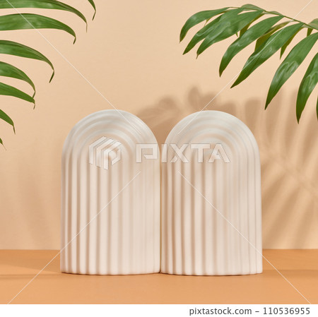 Abstract beige background with white decorative arch and palm leaf and shadow, stage for showcasing products, cosmetics 110536955