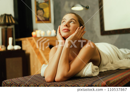 Beautiful woman lies on spa bed in front of wooden sauna cabinet. Tranquility. 110537867
