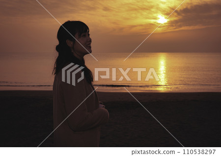 Young woman enjoying the sunset at the sea in winter 110538297