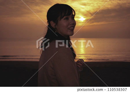 冬天在海邊享受日落的年輕女子 冬天在海邊享受日落的年輕女子 110538307