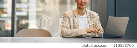 Focused business woman working on laptop sitting the desk on office background and looks camera 110538700
