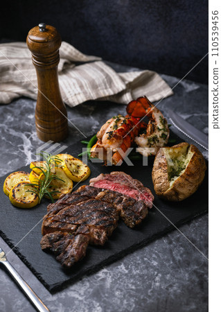 surf and turf, ribeye steak and lobster tail on black marble background 110539456