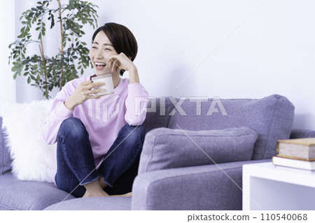 Middle-aged woman relaxing on the sofa while drinking coffee 110540068