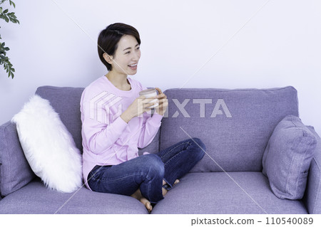 Middle-aged woman relaxing on the sofa while drinking coffee 110540089
