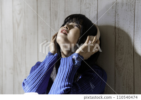 Young woman listening to music on headphones Young woman listening to music on headphones 110540474