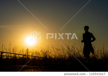 sunset and silhouette of jogger 110541027