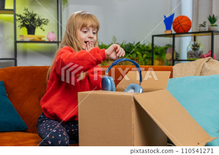 Happy child girl shopper unpacking cardboard box delivery parcel online shopping purchase at home 110541271