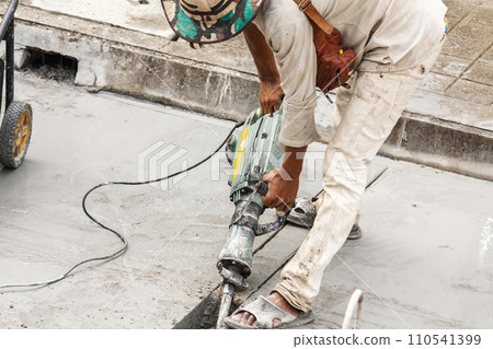 Construction worker using jackhammer drilling concrete surface Construction worker using jackhammer drilling concrete surface 110541399