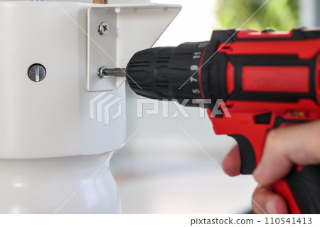 man assembling white table furniture at home using cordless screwdriver man assembling white table furniture at home using cordless screwdriver 110541413