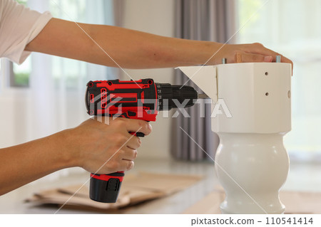 man assembling white table furniture at home using cordless screwdriver man assembling white table furniture at home using cordless screwdriver 110541414