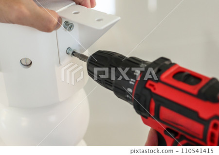 man assembling white table furniture at home using cordless screwdriver man assembling white table furniture at home using cordless screwdriver 110541415